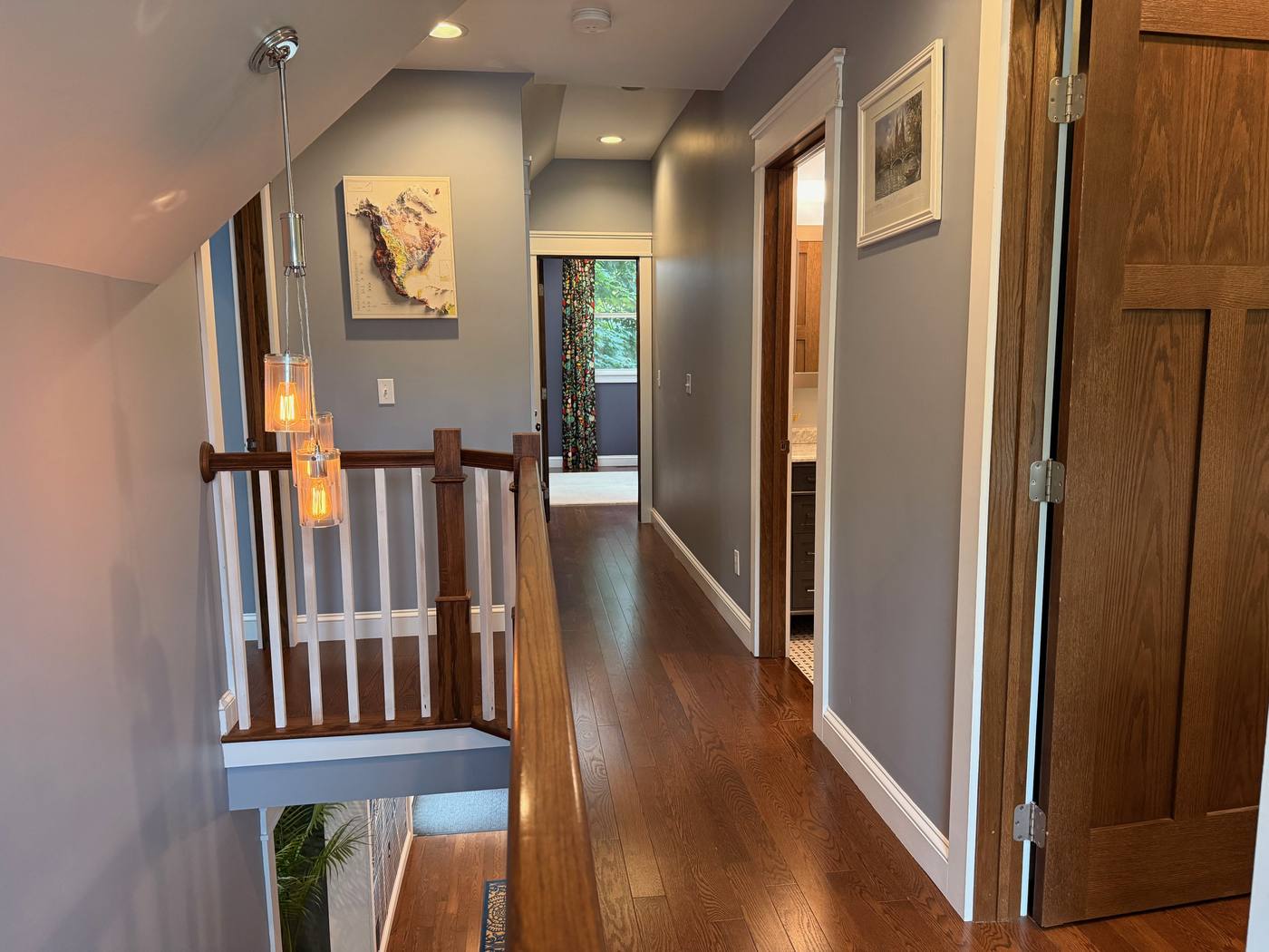Upper hallway with warm pendant lighting and hardwood floors